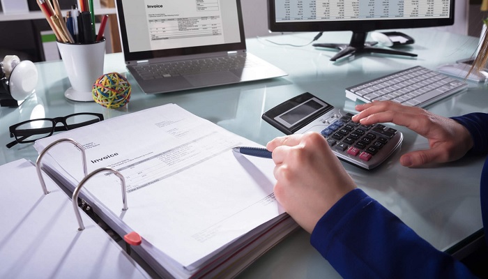 Contador com Fichário, Calculadora e Notebook sobre a mesa.